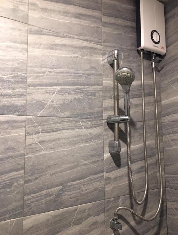 A wall-mounted shower with an electric water heater is shown against grey tiled walls.