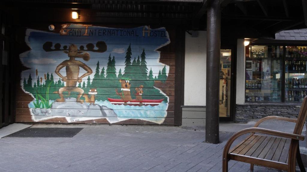 a mural on the side of a building with a bench at Banff International Hostel in Banff