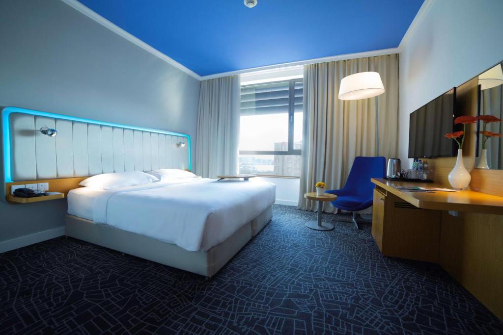 a hotel room with a large bed and a desk at Park Inn by Radisson Abu Dhabi Yas Island in Abu Dhabi