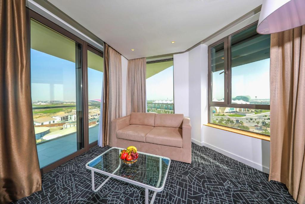 a room with a couch and a table and windows at Park Inn by Radisson Abu Dhabi Yas Island in Abu Dhabi