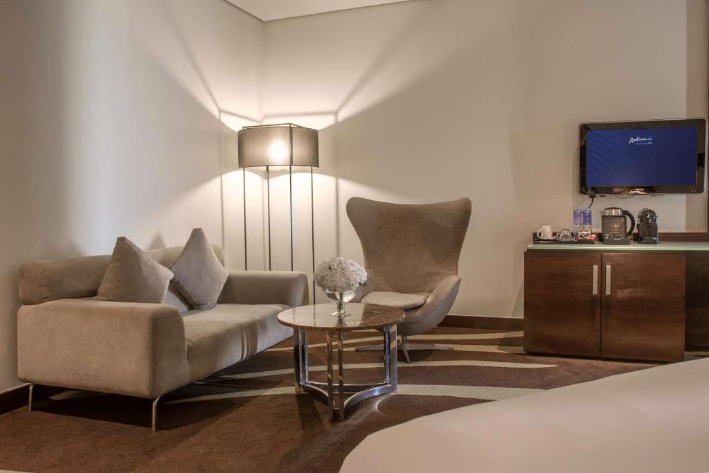 a living room with a couch and a table and a tv at Radisson Blu Hotel, Abu Dhabi Yas Island in Abu Dhabi