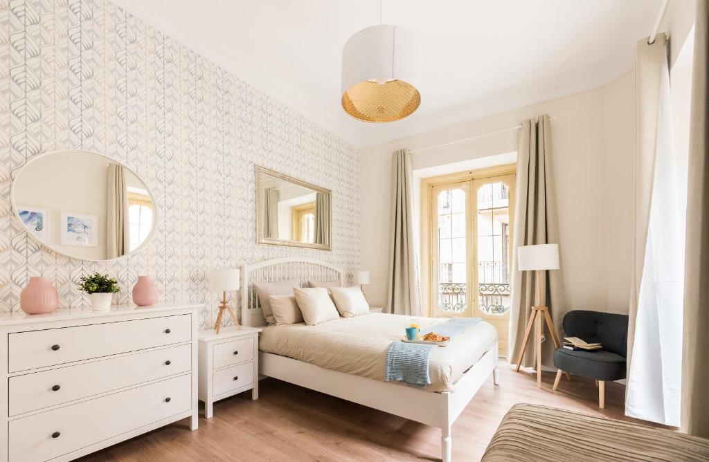 een witte slaapkamer met een bed en een spiegel bij Apartamento en Puerta del Sol in Madrid