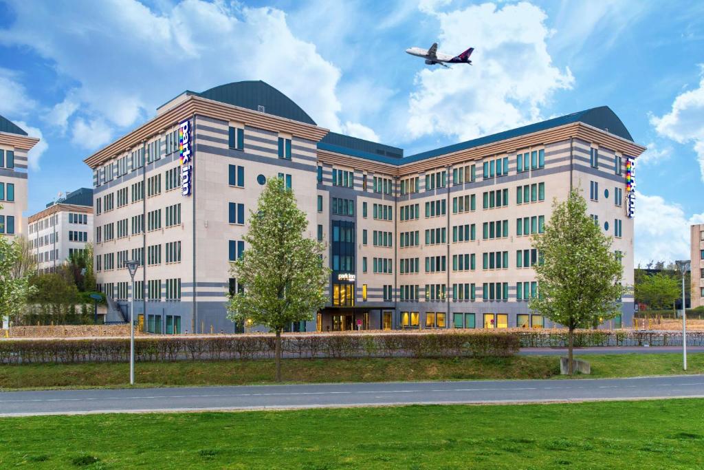 um grande edifício com um avião voando sobre ele em Park Inn By Radisson Brussels Airport em Diegem