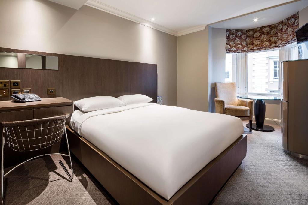 a bedroom with a large white bed and a desk at Radisson Blu Hotel, London Bloomsbury in London
