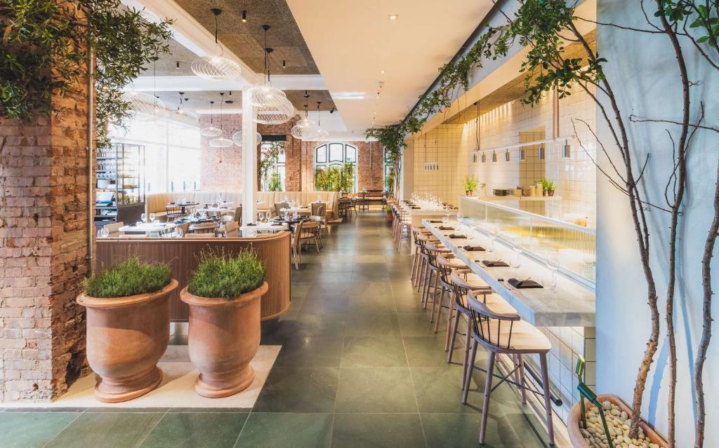 a restaurant with tables and chairs and plants at Radisson Blu Hotel, London Bloomsbury in London