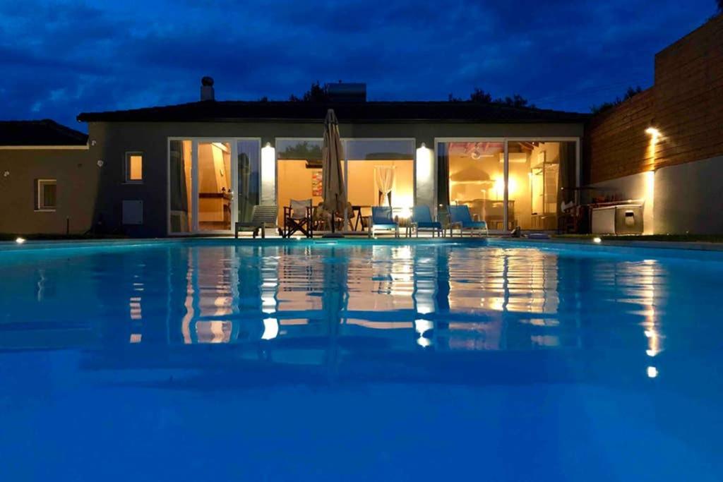 a large swimming pool in front of a house at night at Sunlit Pool House in Posidhonía