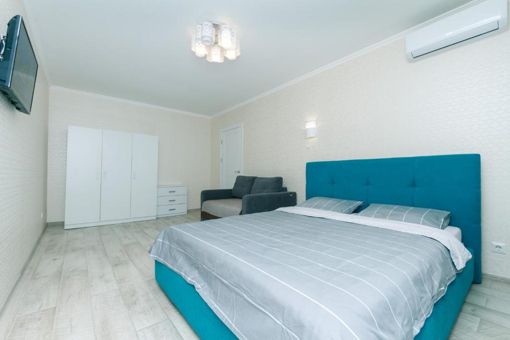 um quarto com uma cama azul e uma cadeira em New apartment on Starokyivska 1/5 em Kiev