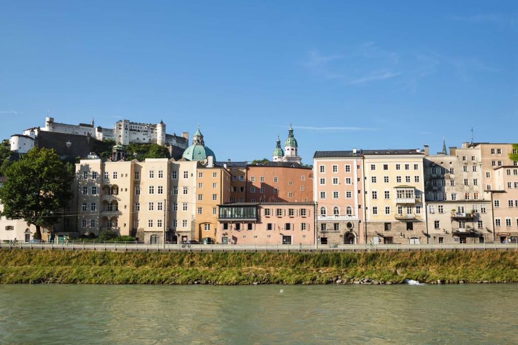 eine Gruppe von Gebäuden neben einem Wasserkörper in der Unterkunft Radisson Blu Hotel Altstadt in Salzburg