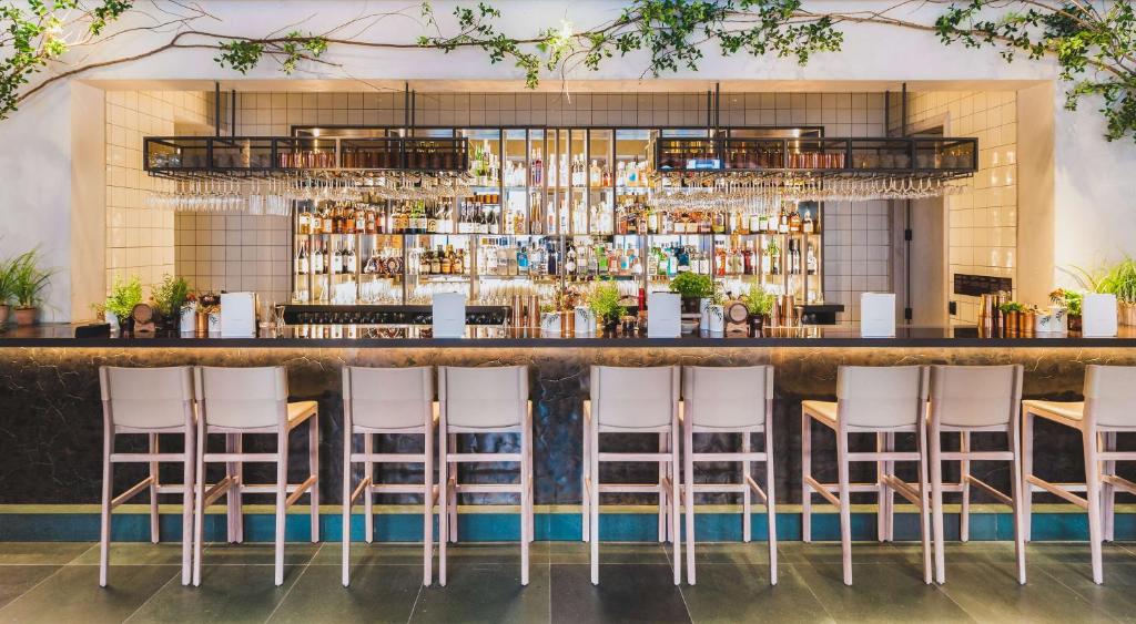 a bar with white stools in front of a counter at Radisson Blu Hotel, London Bloomsbury in London