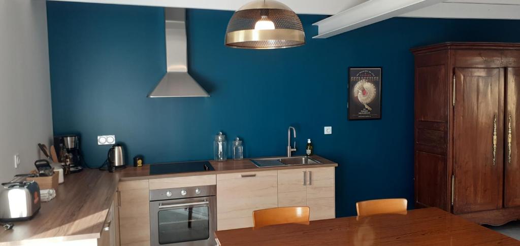 een keuken met blauwe muren en een tafel met stoelen bij Chez Emile in Cherrueix