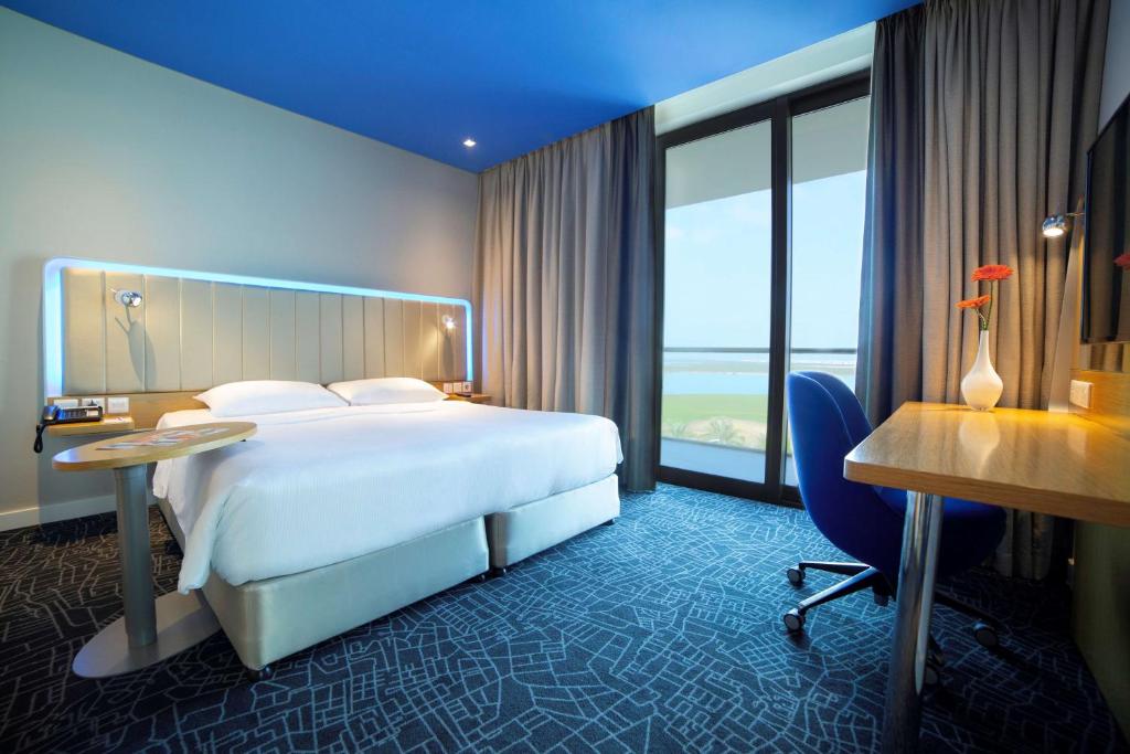 a hotel room with a bed and a desk and window at Park Inn by Radisson Abu Dhabi Yas Island in Abu Dhabi