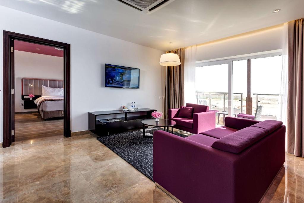 a living room with a purple couch and a bedroom at Park Inn by Radisson Hotel and Residence Duqm in Duqm