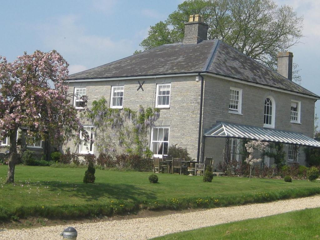 a large gray brick house with a grass yard at Cary Fitzpaine House in Babcary