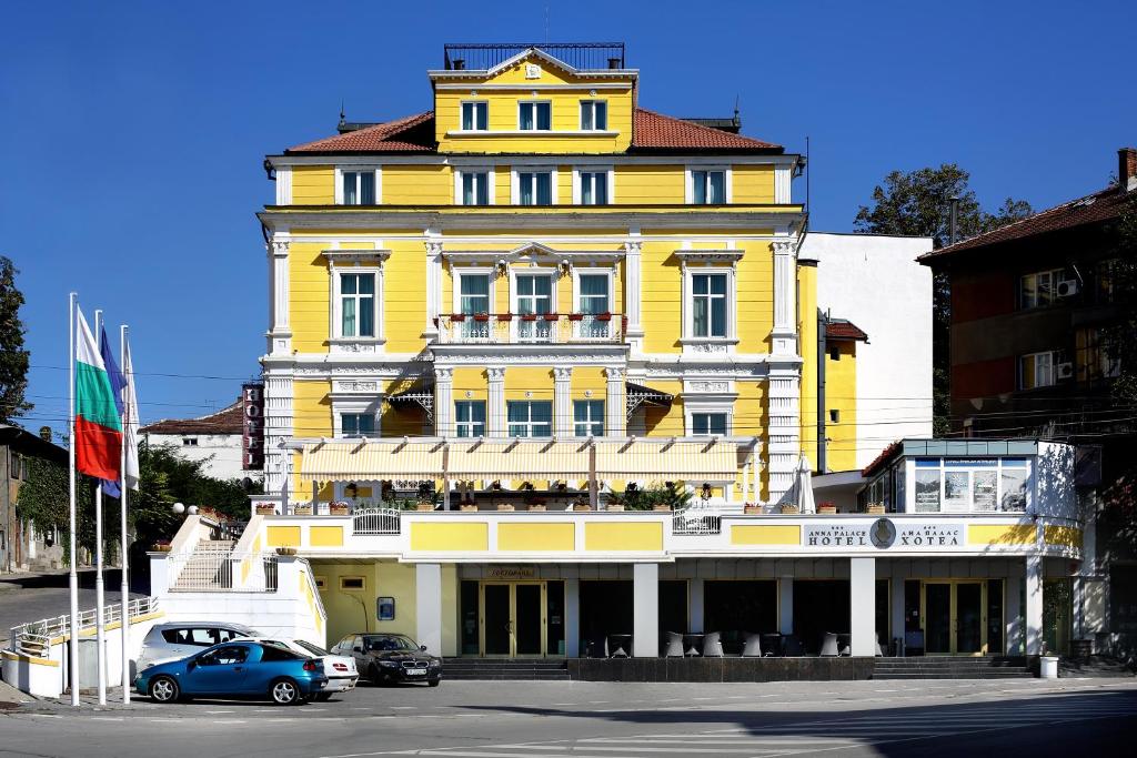 un edificio amarillo con coches estacionados frente a él en Hotel Anna Palace, en Ruse