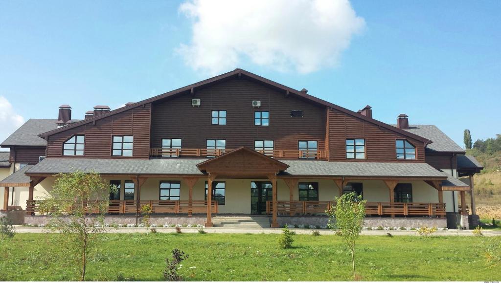 a large wooden house with a gambrel at Alpika Hotel in Belgorod