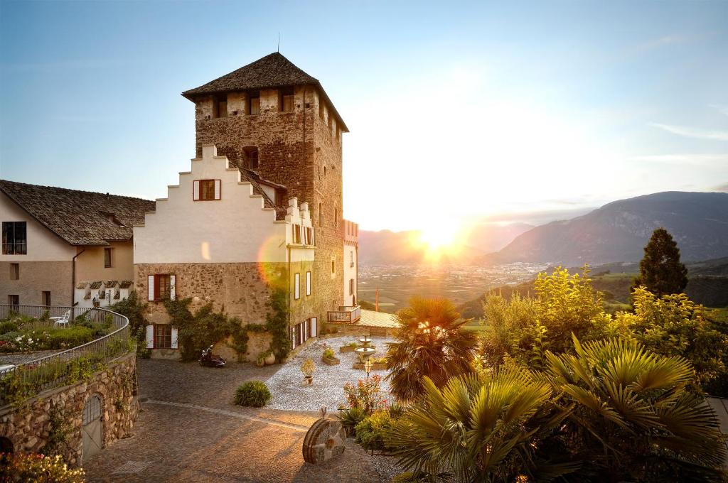 una imagen de un edificio con la puesta de sol en el fondo en Schloss Hotel Korb, en Appiano sulla Strada del Vino