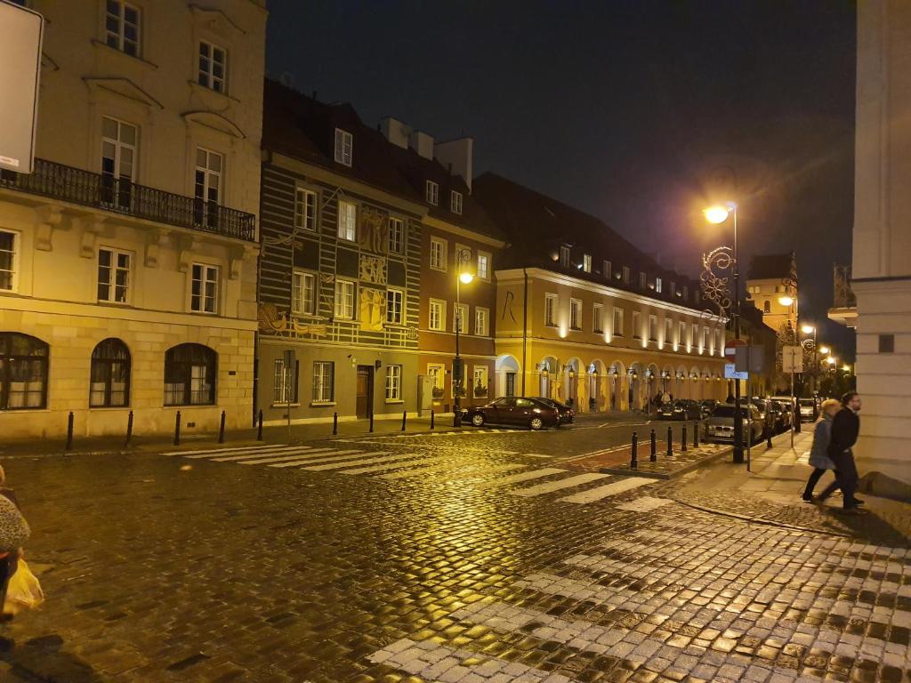 a cobblestone street in a city at night at RentOnline Kościelna Apartment Old Town in Warsaw