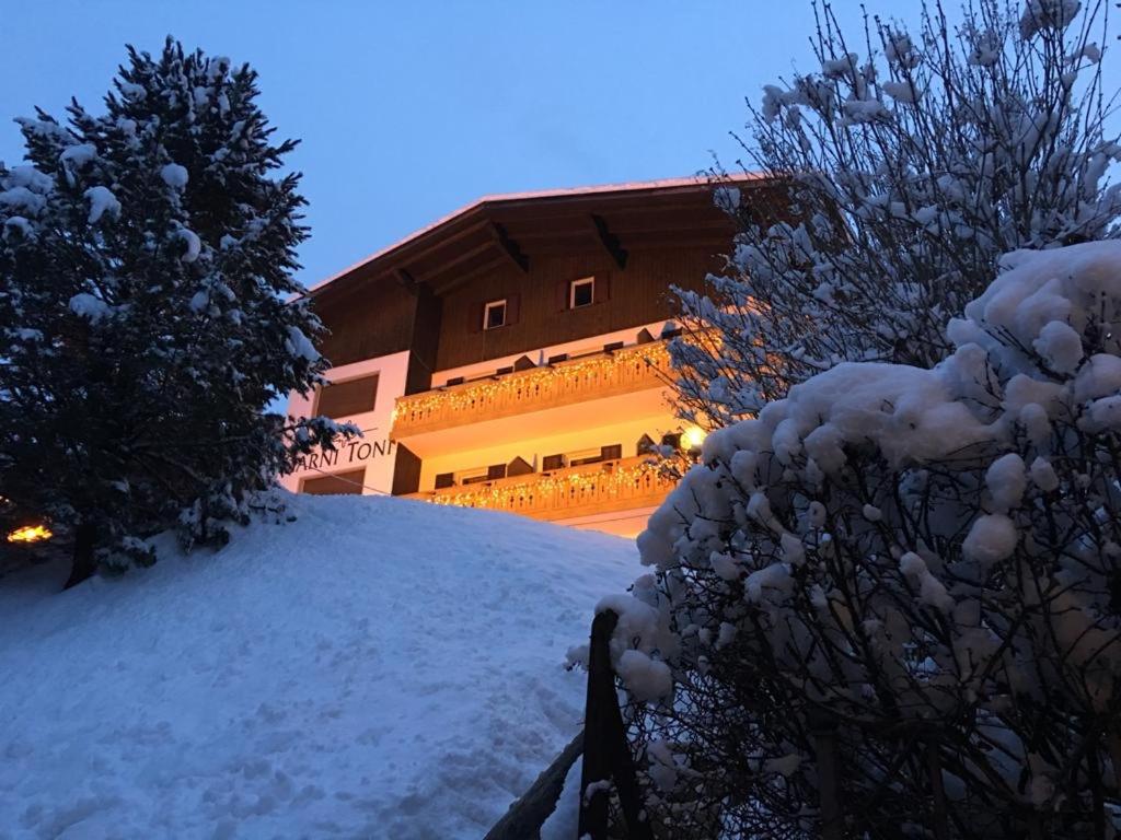 a snow covered hill in front of a building at Garni Toni in Ortisei