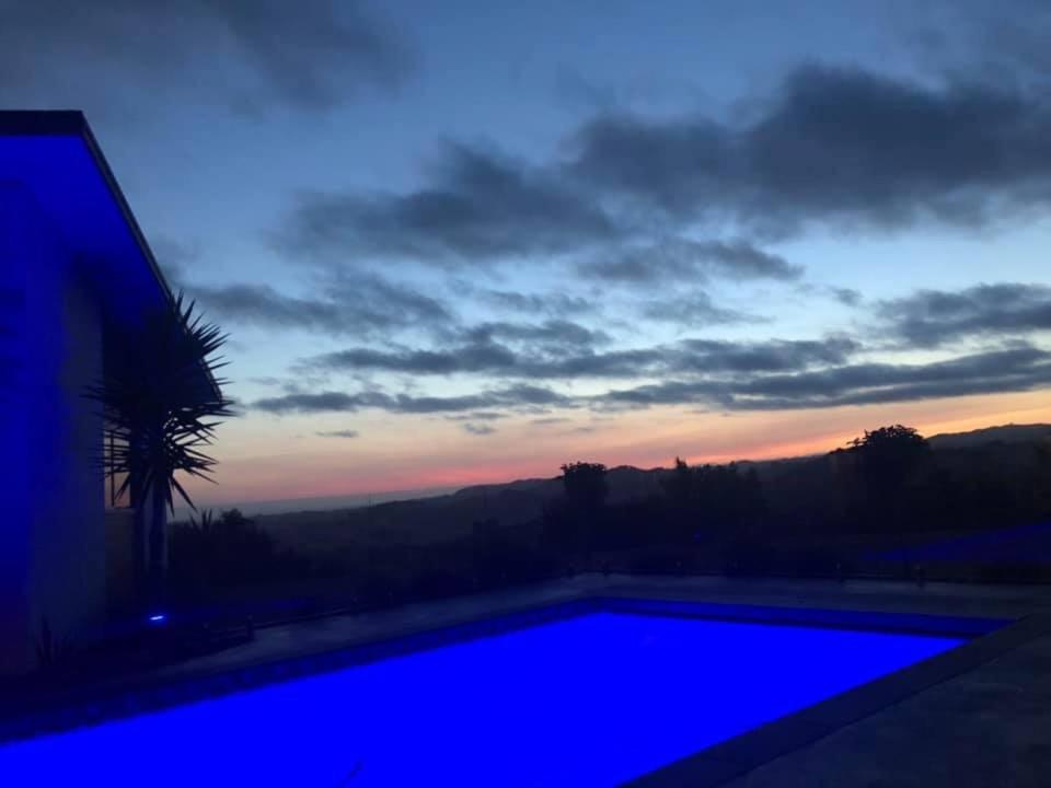 a blue swimming pool with a sunset in the background at Wilsons Retreat - Hosts On-site in Eskdale