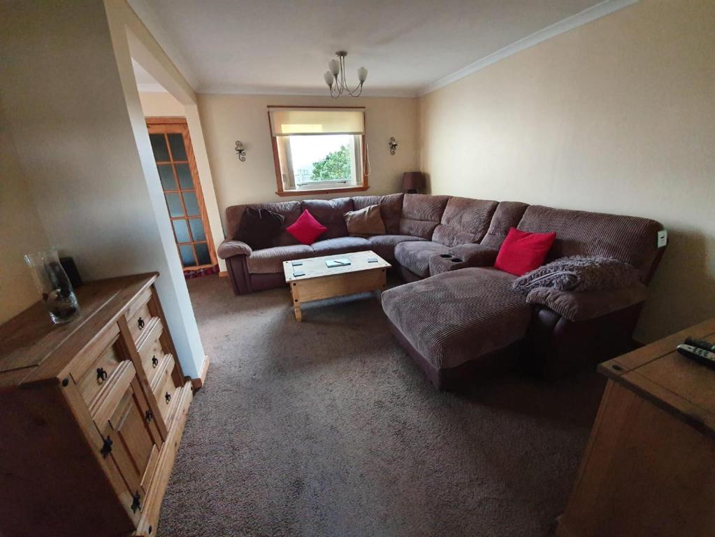 sala de estar con sofá marrón y almohadas rojas en Taigh nam Piobaireach, en Balivanich