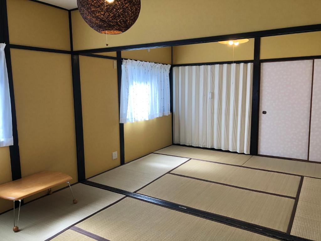 una stanza vuota con tavolo e panca di ゲストハウスAmaなつ ad Amami