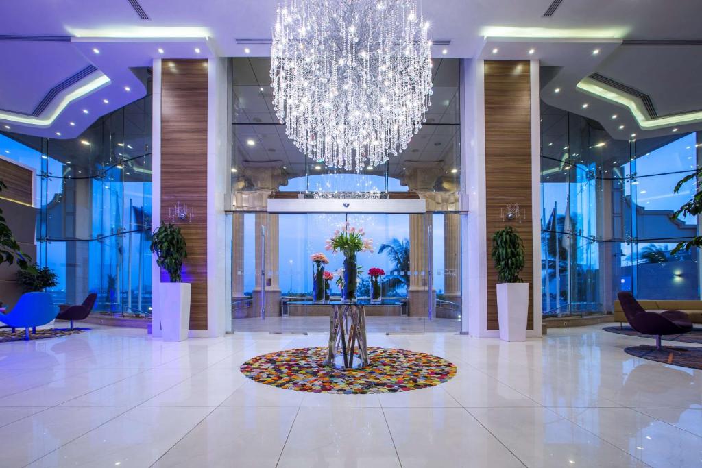 a large lobby with a large chandelier and a table with flowers at Radisson Blu Plaza Jeddah in Jeddah