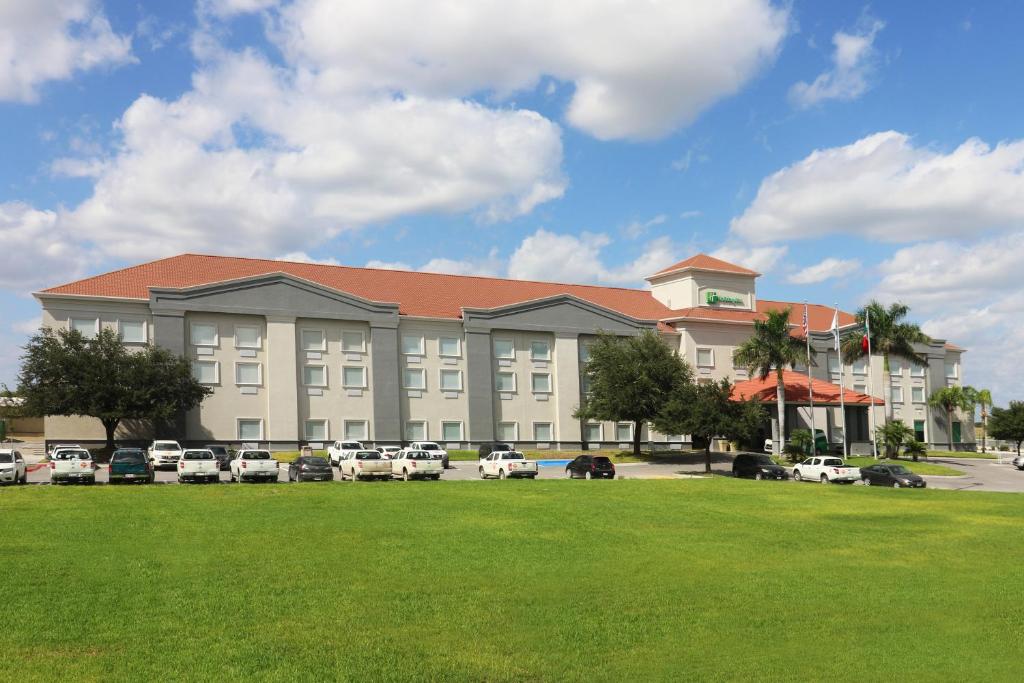 een groot gebouw met auto's geparkeerd op een parkeerplaats bij Holiday Inn Reynosa Industrial Poniente, an IHG Hotel in Reynosa