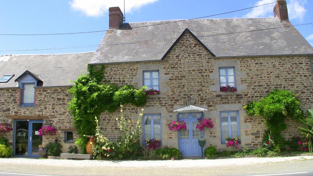 une maison en briques avec des fleurs devant elle dans l'établissement La Bastide du Moulin - Mont St Michel, à Moidrey