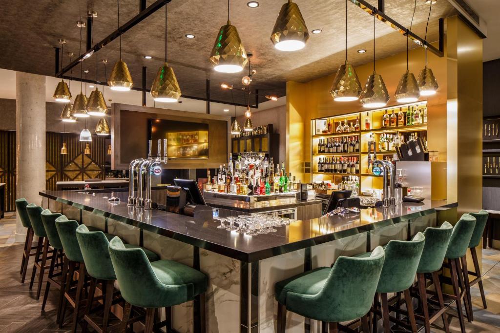 a bar in a restaurant with green chairs at Crowne Plaza Aberdeen Airport by IHG in Dyce