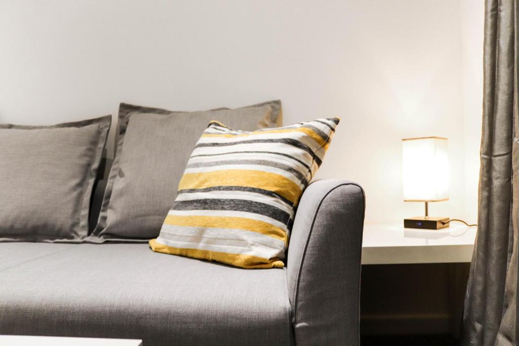 阿士頓的住宿－Stylish - Modern - Serviced Accommodation - In The Heart of Northumberland，一张带条纹枕头的灰色沙发,旁边是一张桌子