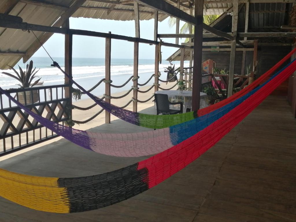 a colorful hammock in a room with the beach at Cabañas Refugio Salomon in Nuquí