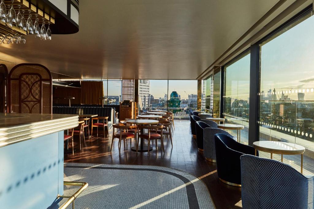 a restaurant with tables and chairs and large windows at Hotel Indigo London - 1 Leicester Square, an IHG Hotel in London