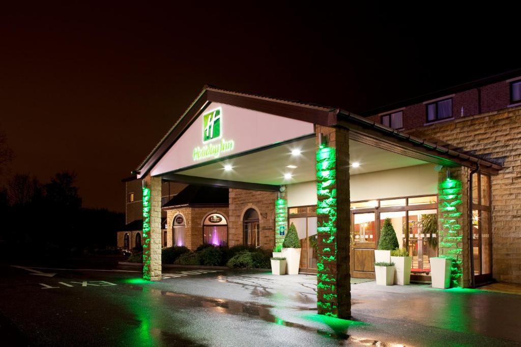 Holiday Inn Barnsley, an IHG Hotel في بارنسلي: واجهة متجر في الليل مع أضواء خضراء