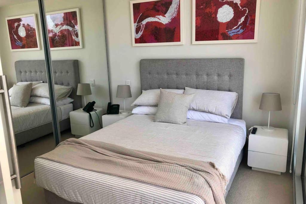 een slaapkamer met een groot bed en 2 spiegels bij The Watson 209 great location Close to CBD in Adelaide