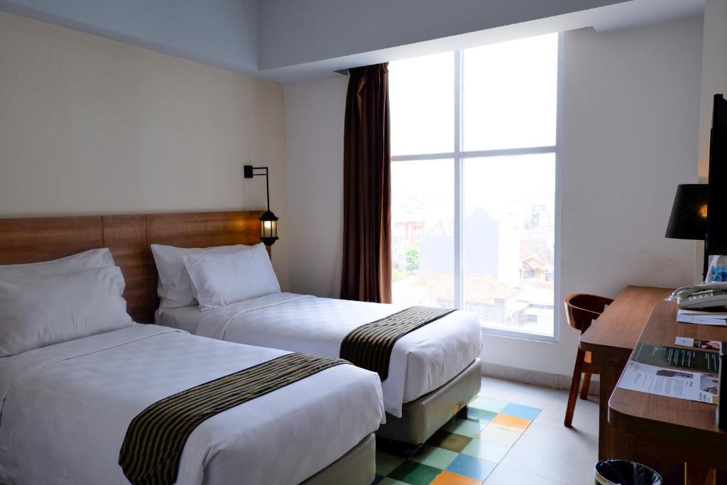 Postel nebo postele na pokoji v ubytování KHAS Tugu Hotel Yogyakarta