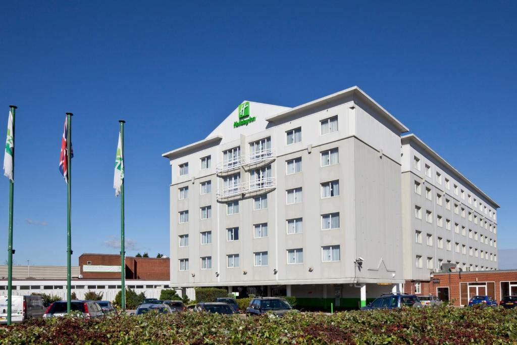 un hôtel blanc avec des voitures garées dans un parking dans l'établissement Holiday Inn Basildon, an IHG Hotel, à Basildon