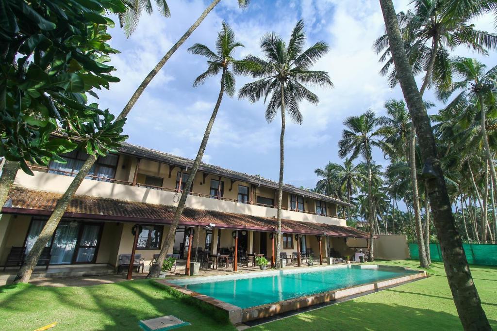 a resort with a swimming pool and palm trees at Maresia Beach Villa in Wadduwa