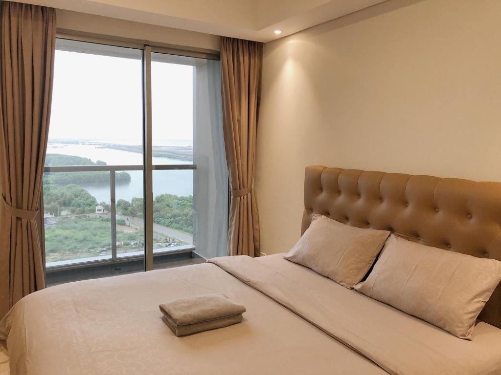 雅加達的住宿－Gold Coast PIK Sea View Apartments by LongeSuites，一间卧室设有一张大床和大窗户