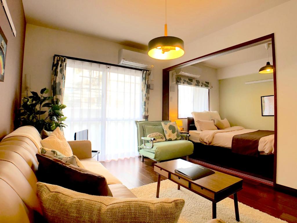 un soggiorno con divano, letto e specchio di Luana Lea Karate Kaikan Mae a Tomigusuku
