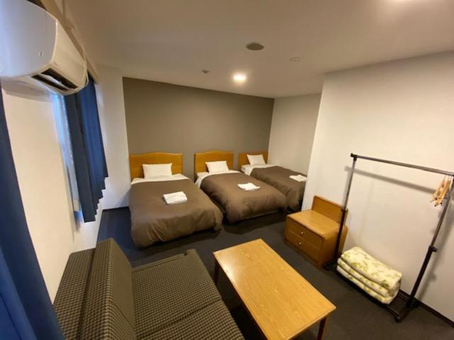 Hotel New Yutaka في إيزوميسانو: غرفة بسريرين وطاولة فيها