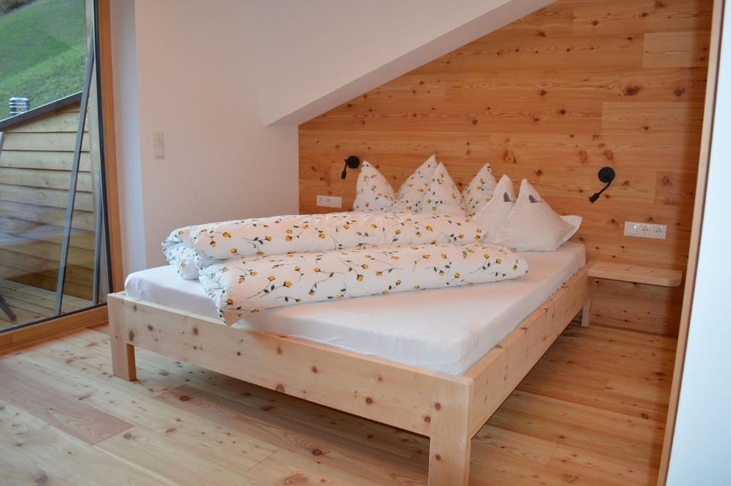 een slaapkamer met een bed met een houten muur bij Steinhof in Val di Mezzo