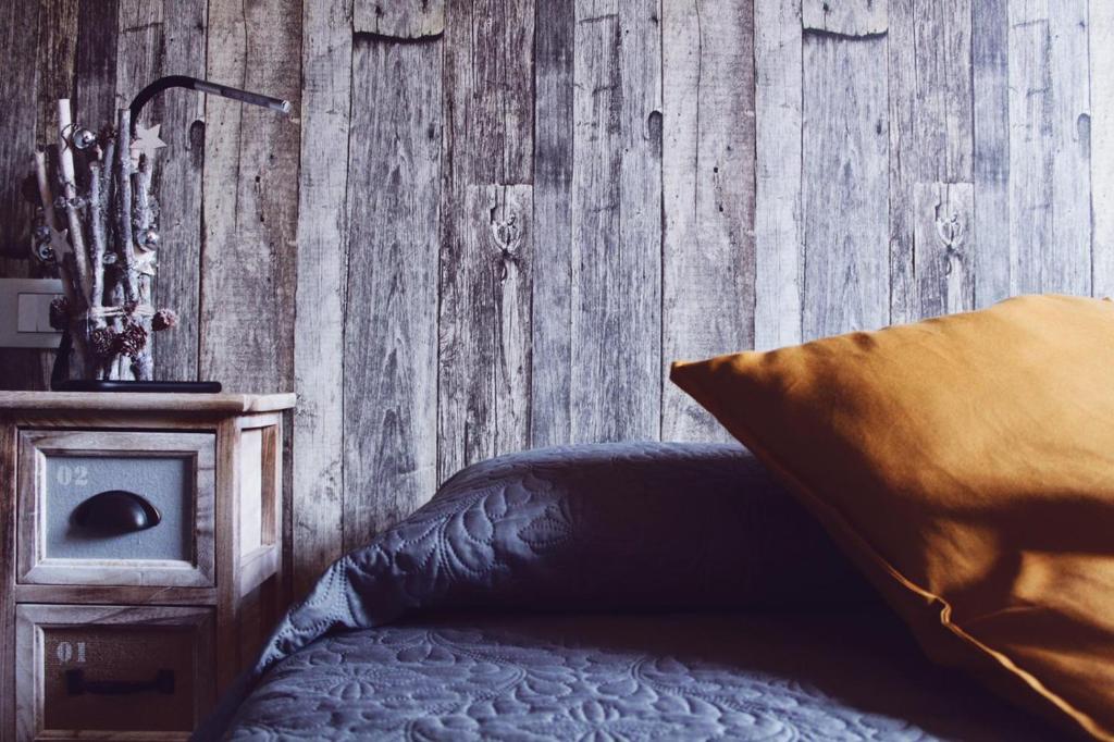 1 dormitorio con 1 cama y pared de madera en ApartHotel Le Sirene - CHALET en Tivoli