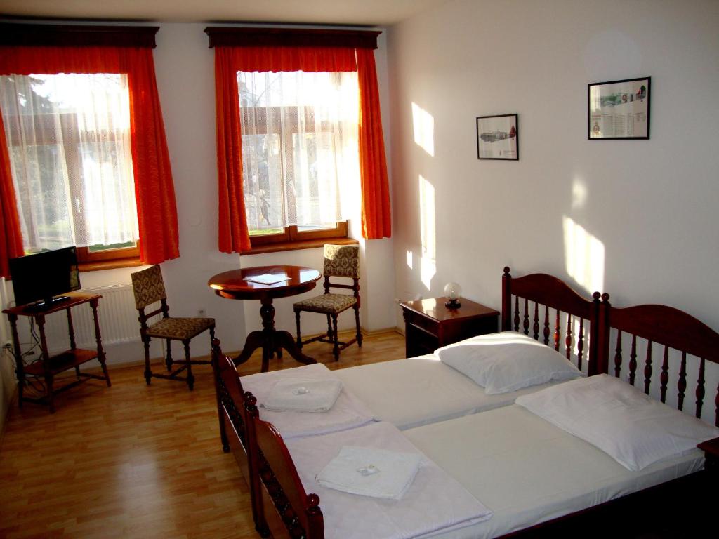 a bedroom with a bed and a table and windows at Penzion Aviatik in Čáslav