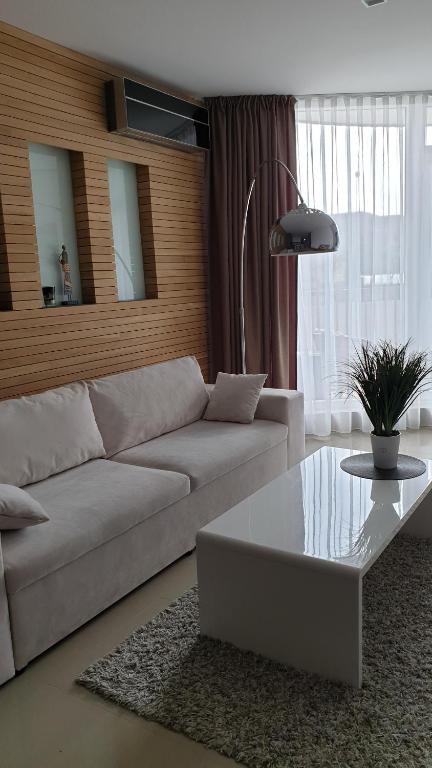 uma sala de estar com um sofá branco e uma mesa de centro em Nomuojami apartamentai 600m iki juros em Šventoji