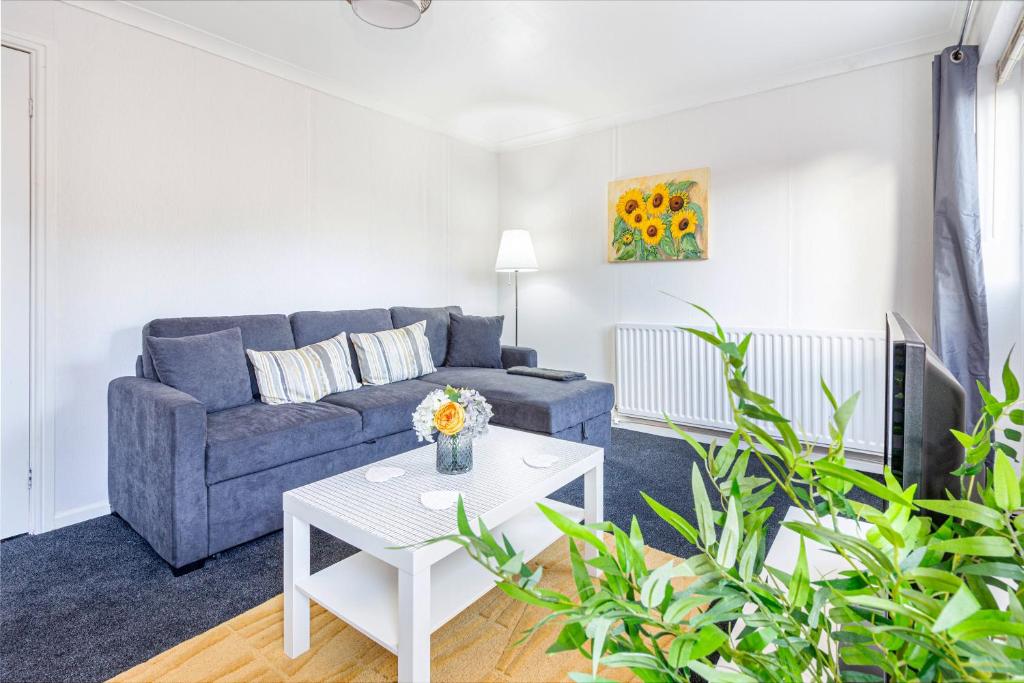 uma sala de estar com um sofá azul e uma mesa em 4 Bedrooms Cosy Family Home, Super-Fast Wi-Fi, Free Parking, The Saddlers Gateway em Walsall