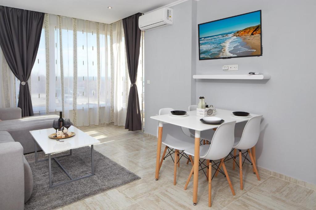 sala de estar con mesa blanca y sillas en Niko's Sea View Apartments Deluxe en Nesebar