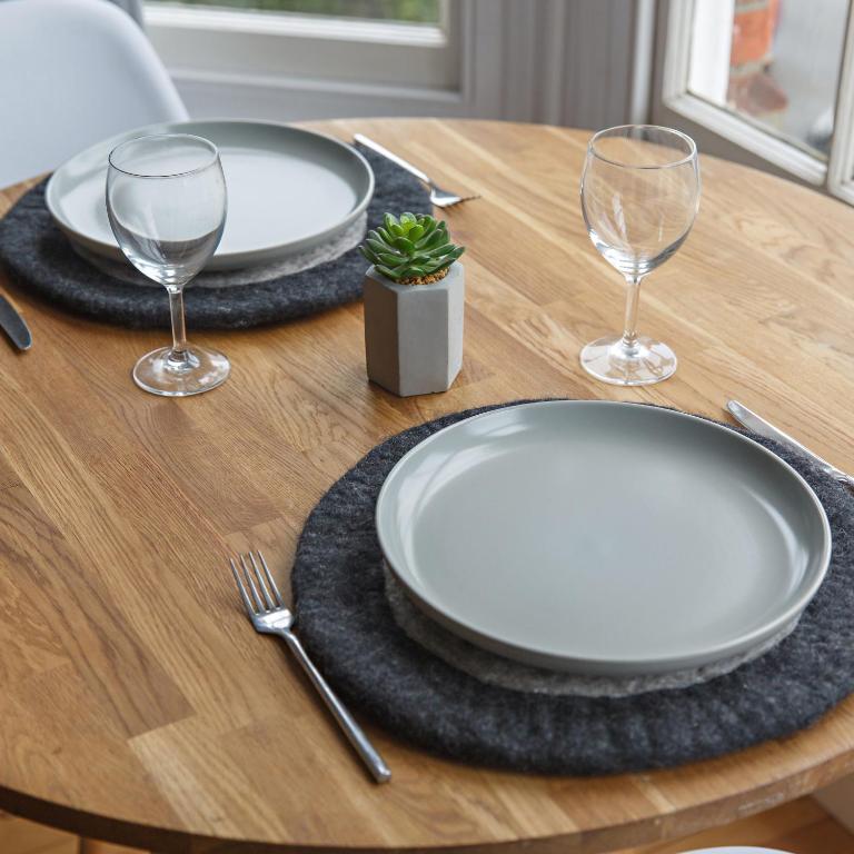 a table with two white plates and two wine glasses at The Sands Sheringham in Sheringham