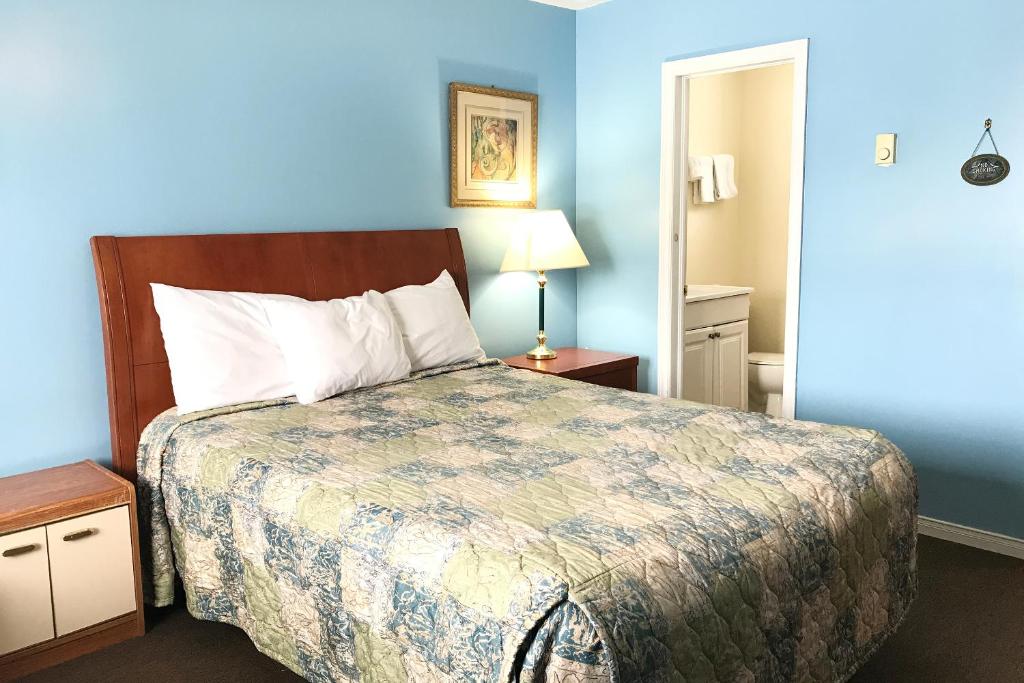 a bedroom with a bed and a blue wall at Bayside Motel Trenton in Trenton