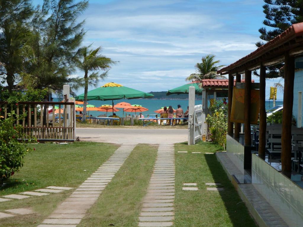 a walkway leading to a beach with umbrellas at Itaoca Pousada Camping in Itaipava