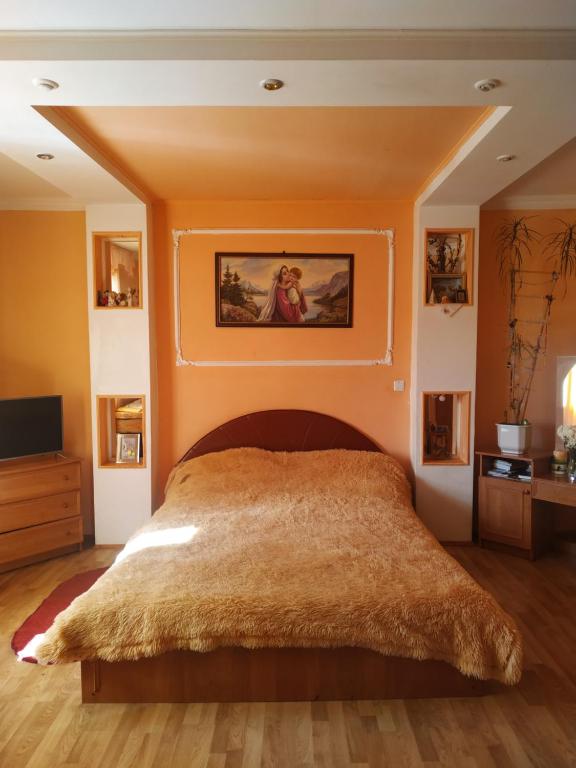 ein Schlafzimmer mit einem großen Bett und einer orangefarbenen Wand in der Unterkunft Садиба у пані Марії in Worochta